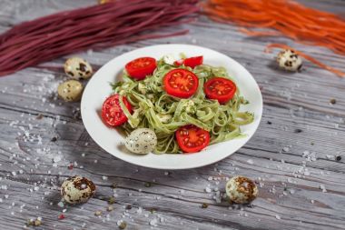 Mozzarella peyniri, yeşillik ve Fransız hardalı, bıldırcın yumurtası ve kiraz domates bir plaka, biber ve karanlık bir arka plan üzerinde gri bir ahşap masa üzerinde büyük deniz tuzu ile yeşil ıspanaklı makarna