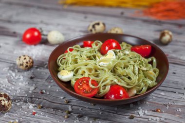 Mozzarella peyniri, yeşillik ve Fransız hardalı, bıldırcın yumurtası ve kiraz domates bir plaka, biber ve karanlık bir arka plan üzerinde gri bir ahşap masa üzerinde büyük deniz tuzu ile yeşil ıspanaklı makarna