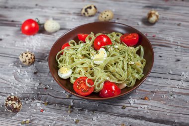 Mozzarella peyniri, yeşillik ve Fransız hardalı, bıldırcın yumurtası ve kiraz domates bir plaka, biber ve karanlık bir arka plan üzerinde gri bir ahşap masa üzerinde büyük deniz tuzu ile yeşil ıspanaklı makarna