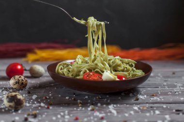 Mozzarella peyniri, yeşillik ve Fransız hardalı, bıldırcın yumurtası ve kiraz domates bir plaka, biber ve karanlık bir arka plan üzerinde gri bir ahşap masa üzerinde büyük deniz tuzu ile yeşil ıspanaklı makarna