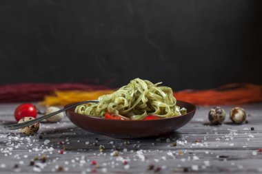 Mozzarella peyniri, yeşillik ve Fransız hardalı, bıldırcın yumurtası ve kiraz domates bir plaka, biber ve karanlık bir arka plan üzerinde gri bir ahşap masa üzerinde büyük deniz tuzu ile yeşil ıspanaklı makarna