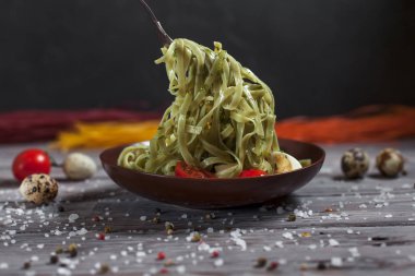 Mozzarella peyniri, yeşillik ve Fransız hardalı, bıldırcın yumurtası ve kiraz domates bir plaka, biber ve karanlık bir arka plan üzerinde gri bir ahşap masa üzerinde büyük deniz tuzu ile yeşil ıspanaklı makarna