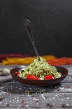 Mozzarella peyniri, yeşillik ve Fransız hardalı, bıldırcın yumurtası ve kiraz domates bir plaka, biber ve karanlık bir arka plan üzerinde gri bir ahşap masa üzerinde büyük deniz tuzu ile yeşil ıspanaklı makarna