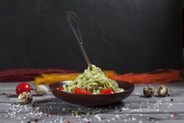 Mozzarella peyniri, yeşillik ve Fransız hardalı, bıldırcın yumurtası ve kiraz domates bir plaka, biber ve karanlık bir arka plan üzerinde gri bir ahşap masa üzerinde büyük deniz tuzu ile yeşil ıspanaklı makarna