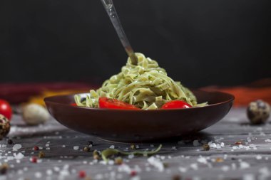 Mozzarella peyniri, yeşillik ve Fransız hardalı, bıldırcın yumurtası ve kiraz domates bir plaka, biber ve karanlık bir arka plan üzerinde gri bir ahşap masa üzerinde büyük deniz tuzu ile yeşil ıspanaklı makarna