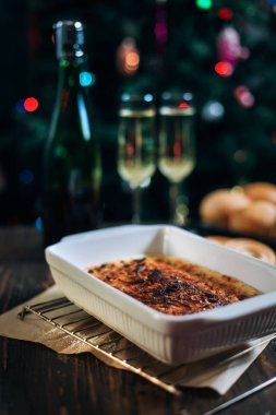 bir yeni yıl'ın tablo, peynir pasta çikolata, mandalina, üzüm, bisküvi, şampanya ve iki bardak dekore edilmiş bir Noel ağacı ışıkları ile fon karşı