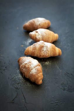 bir meyve dolgulu dört ay çöreği ile koyu gri arka plan üzerine pudra şekeri serpilir