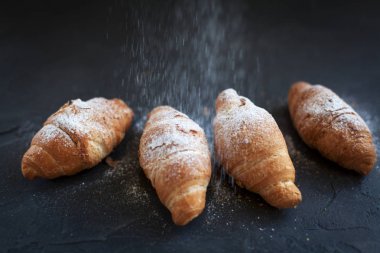 bir meyve dolgulu dört ay çöreği ile koyu gri arka plan üzerine pudra şekeri serpilir