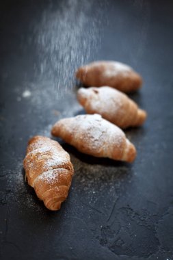 bir meyve dolgulu dört ay çöreği ile koyu gri arka plan üzerine pudra şekeri serpilir