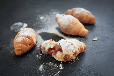 bir meyve dolgulu dört ay çöreği ile koyu gri arka plan üzerine pudra şekeri serpilir