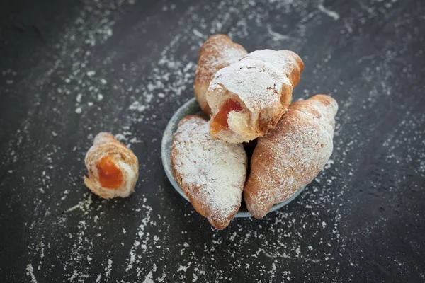 Vier Croissants mit Fruchtfüllung, bestreut mit Puderzucker auf dunkelgrauem Hintergrund — Stockfoto