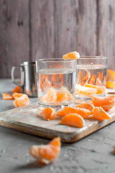 orange drink, tangerines, white cutting board on light gray background