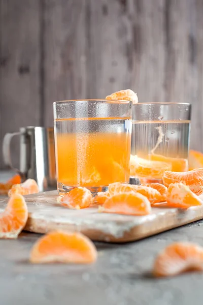 orange drink, tangerines, white cutting board on light gray background