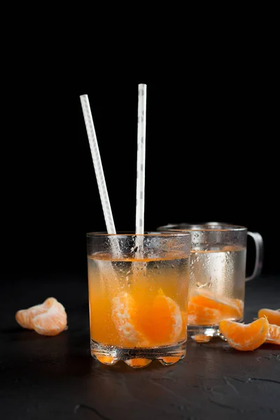 Bebida cor-de-laranja, tangerinas e limão sobre um fundo escuro — Fotografia de Stock