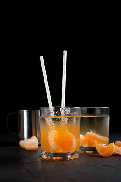 Bebida cor-de-laranja, tangerinas e limão sobre um fundo escuro — Fotografia de Stock