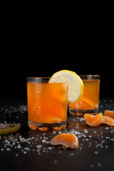 orange drink, tangerines and lemon on a dark background