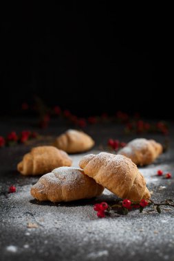 birkaç bütün kruvasan kırıntıları ile toz şeker ve karanlık bir arka plan üzerinde kırmızı meyveler