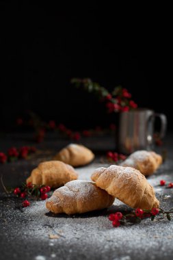 birkaç bütün kruvasan kırıntıları ile toz şeker ve karanlık bir arka plan üzerinde kırmızı meyveler
