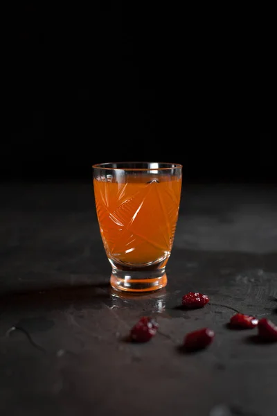 Un bicchiere di arancia fresca e bacche rosse su sfondo scuro — Foto Stock
