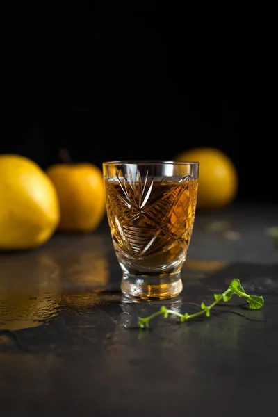 Un vaso con una bebida, bayas rojas, menta y manzanas amarillas sobre un fondo oscuro — Foto de Stock