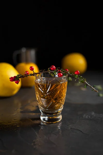 Een glas met een drankje, rode bessen, mint en gele appels op een donkere achtergrond — Stockfoto