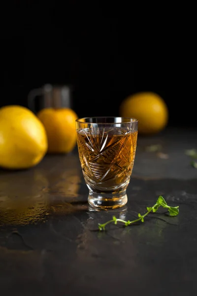 Un vaso con una bebida, bayas rojas, menta y manzanas amarillas sobre un fondo oscuro — Foto de Stock