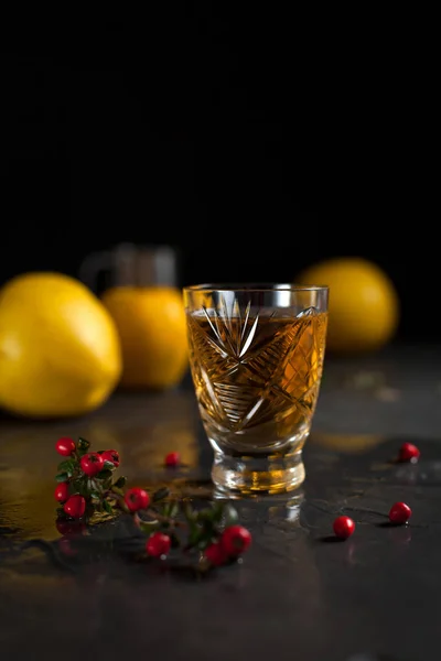 A glass with a drink, red berries, mint and yellow apples on a dark background — Stock Photo, Image