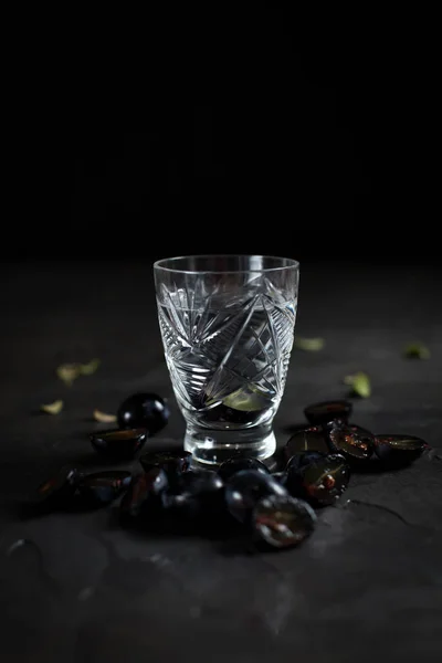 Vidro com uma bebida transparente e segmentos de uva em um fundo escuro — Fotografia de Stock