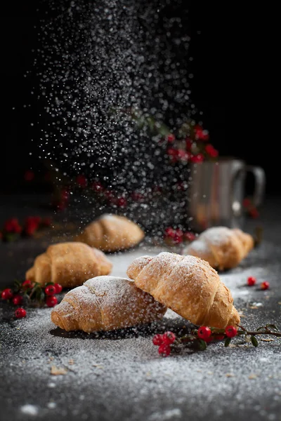 Several whole croissants with crumbs, powdered sugar and red berries on a dark background — Stock Photo, Image