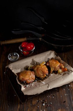 bir gevrek kabuk, baharatlar, pişirme kağıdı, büyük deniz tuzu koyu ahşap zemin üzerinde siyah bir plaka üzerinde sulu tavuk pişmiş