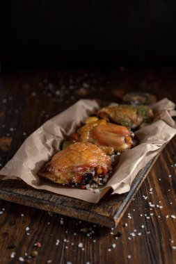 bir gevrek kabuk, baharatlar, pişirme kağıdı, büyük deniz tuzu koyu ahşap zemin üzerinde siyah bir plaka üzerinde sulu tavuk pişmiş