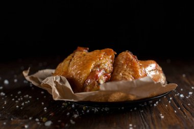 bir gevrek kabuk, baharatlar, pişirme kağıdı, büyük deniz tuzu koyu ahşap zemin üzerinde siyah bir plaka üzerinde sulu tavuk pişmiş