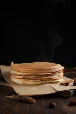 bir yığın krep, çilek, tanımlama bilgileri, ekşi krema ve koyu ahşap bir masa şurubu