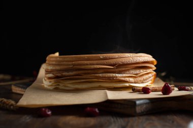 bir yığın krep, çilek, tanımlama bilgileri, ekşi krema ve koyu ahşap bir masa şurubu