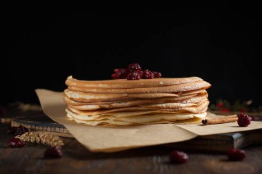 bir yığın krep, çilek, tanımlama bilgileri, ekşi krema ve koyu ahşap bir masa şurubu