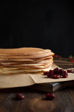 bir yığın krep, çilek, tanımlama bilgileri, ekşi krema ve koyu ahşap bir masa şurubu
