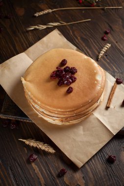 bir yığın krep, çilek, tanımlama bilgileri, ekşi krema ve koyu ahşap bir masa şurubu