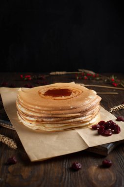 bir yığın krep, çilek, tanımlama bilgileri, ekşi krema ve koyu ahşap bir masa şurubu