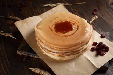 bir yığın krep, çilek, tanımlama bilgileri, ekşi krema ve koyu ahşap bir masa şurubu