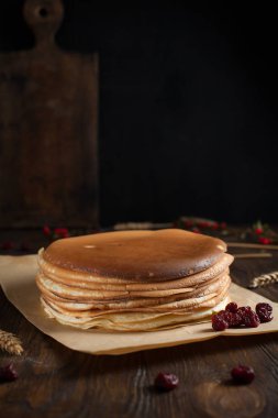 bir yığın krep, çilek, bisküvi ve parşömen üzerine koyu ahşap bir masa üzerinde bir kesme tahtası