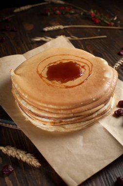 bir yığın krep, çilek, tanımlama bilgileri, ekşi krema ve koyu ahşap bir masa şurubu