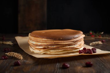 bir yığın krep, çilek, bisküvi ve parşömen üzerine koyu ahşap bir masa üzerinde bir kesme tahtası