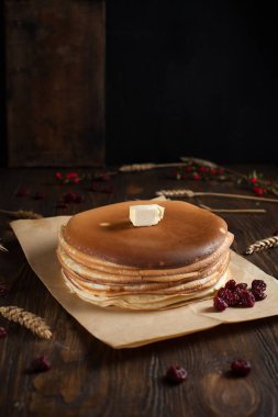 bir yığın krep, çilek, tanımlama bilgileri, tereyağı ve parşömen üzerine koyu ahşap bir masa üzerinde bir kesme tahtası