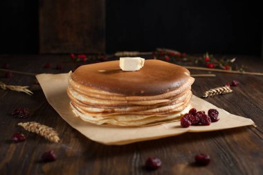 bir yığın krep, çilek, tanımlama bilgileri, tereyağı ve parşömen üzerine koyu ahşap bir masa üzerinde bir kesme tahtası