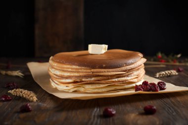 bir yığın krep, çilek, tanımlama bilgileri, tereyağı ve parşömen üzerine koyu ahşap bir masa üzerinde bir kesme tahtası