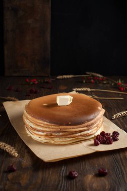 bir yığın krep, çilek, tanımlama bilgileri, tereyağı ve parşömen üzerine koyu ahşap bir masa üzerinde bir kesme tahtası