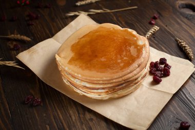 bir yığın krep, çilek, tanımlama bilgileri, tereyağı ve parşömen üzerine koyu ahşap bir masa üzerinde bir kesme tahtası