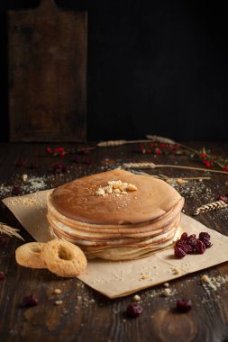 bir yığın krep, çilek, bisküvi ve parşömen üzerine koyu ahşap bir masa üzerinde bir kesme tahtası