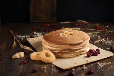 bir yığın krep, çilek, bisküvi ve parşömen üzerine koyu ahşap bir masa üzerinde bir kesme tahtası