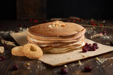 bir yığın krep, çilek, bisküvi ve parşömen üzerine koyu ahşap bir masa üzerinde bir kesme tahtası